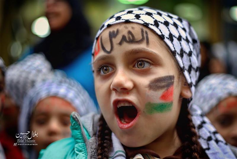 A girl with a Palestinian flag and Arabic that read "Jerusalem is for us"...