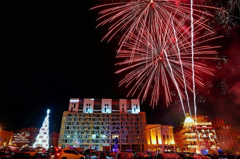 Fireworks go off near a giant Christmas tree, set in front of Martyrs’...
