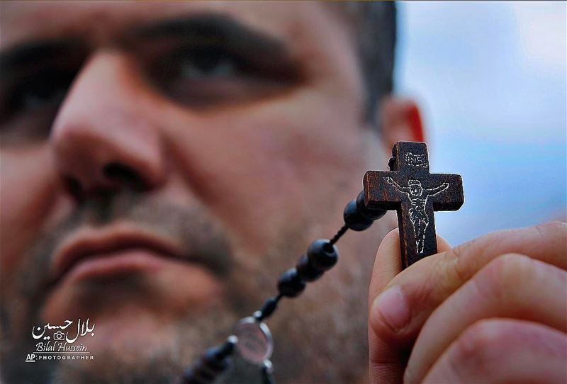 Iraqi Christian Samer Younan who lives in Lebanon holds a cross during a...