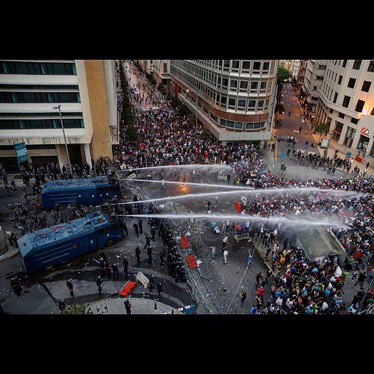 Lebanese activists shout anti-government slogans as they are sprayed by...