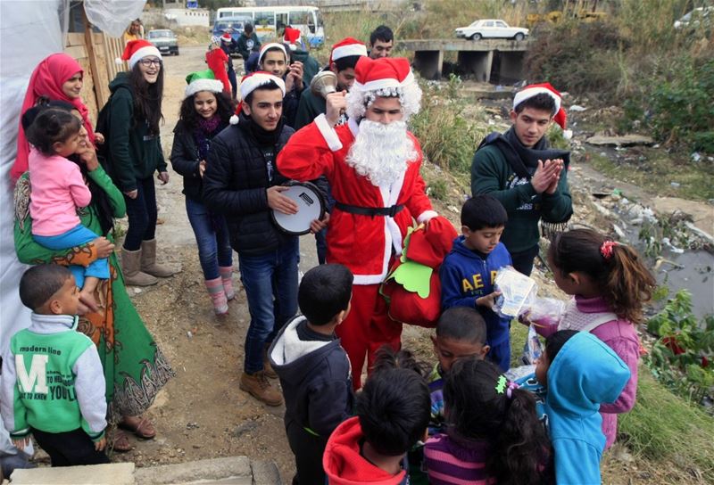 Students at the Evangelical School for Arts distribute Christmas gifts to Syrian refugees in Saida. 