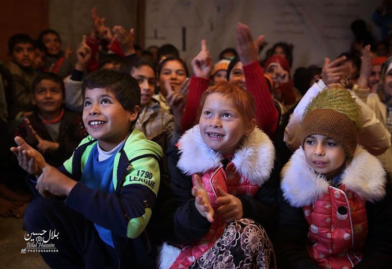 Syrian refugee children respond to their teacher inside a tent that has...