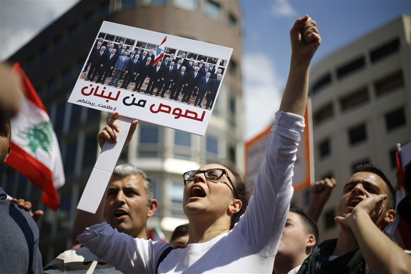 A demonstrator with a photo of the government written on it “Thieves of Lebanon”, in Beirut. (Bilal Hussein / AP) via pow.photos