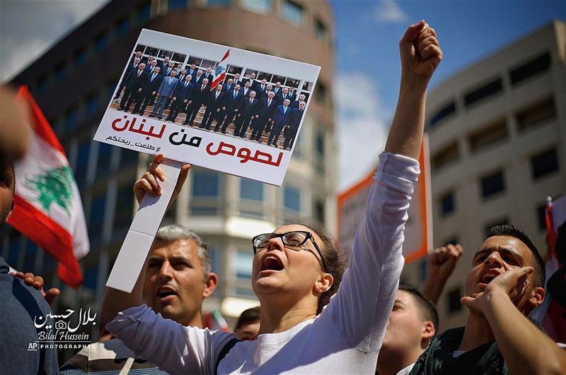 A Lebanese anti-government demonstrator holds a sign with a photo of the...