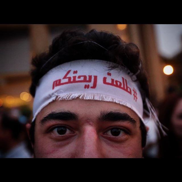 A Lebanese anti-government protester wears a headband with Arabic that...