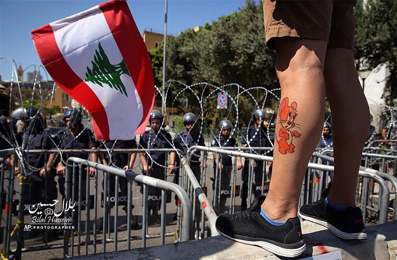 A Lebanese anti-government protester, with a cartoon character tattooed on...