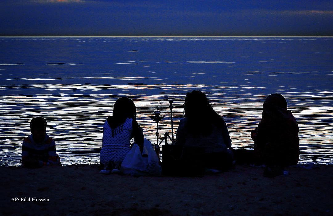 A Lebanese family sits as they smoke a water pipe on the beach at the...
