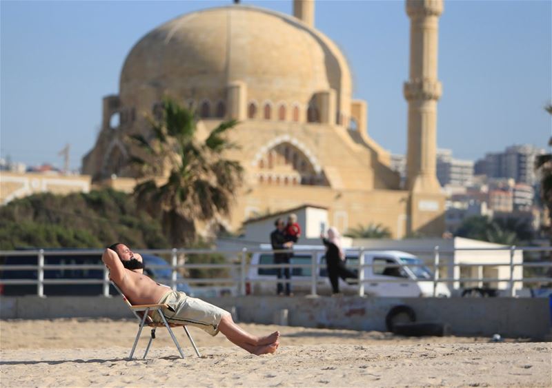 A man sunbathes at a beach in Sidon. (Ali Hashisho / REUTERS)