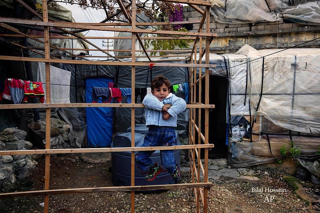A Syrian refugee boy plays outside his family tent, at a Syrian refugee...