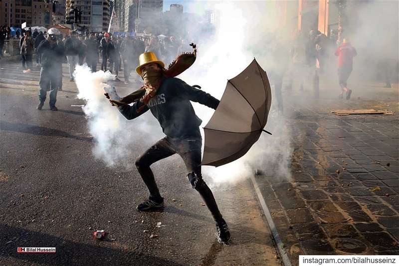 An anti-government demonstrator throws back a tear gas canister towards...