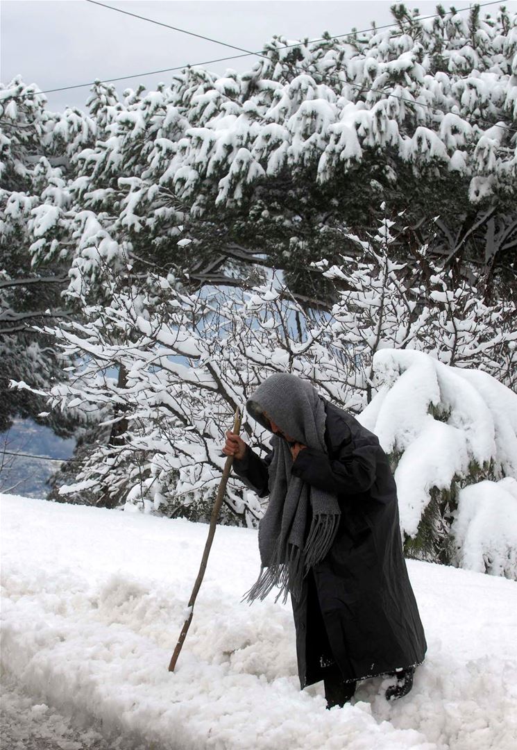 An elderly woman walking in the middle of the snow in Lebanon. (Ali Mohamad)