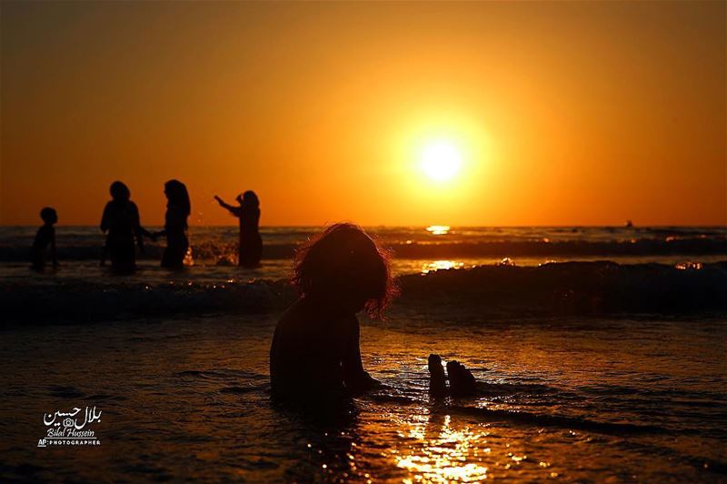 An Iraqi family swims as they spend a day while the sun sets over the...