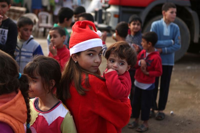 Chloe, holds a Syrian refugee during a gift distribution by the “Mission de Vie” in a slum in the town of Dbayeh. (PATRICK BAZ / AFP)