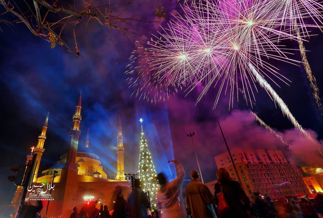 Fireworks go off near a giant Christmas tree, set in front of Muhammad al-A