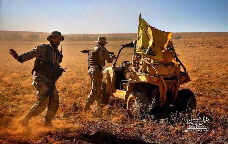 Hezbollah fighters stand near a four-wheel motorcycle positioned at the...