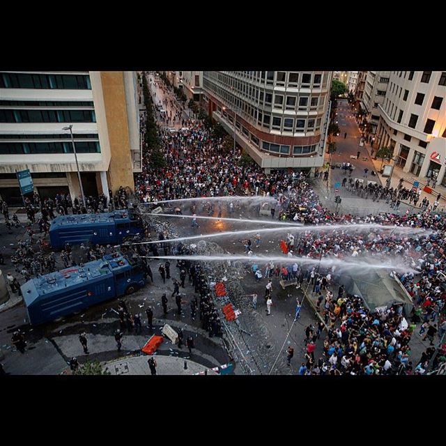 Lebanese activists shout anti-government slogans as they are sprayed by...
