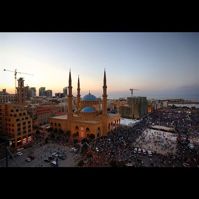 Lebanese anti-government protesters wave their national flags and holds...