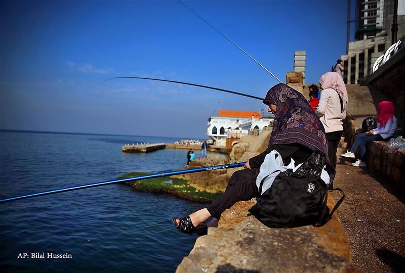 Lebanese fisherwomen sit on a breakwater along the Beirut coastline, as...