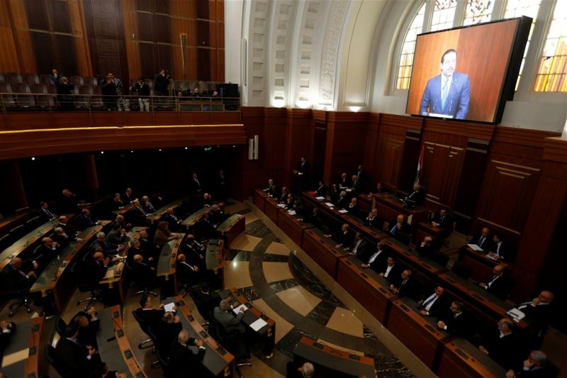 Members of the Parliament watching as Prime Minister Saad al-Hariri talks on a screen.