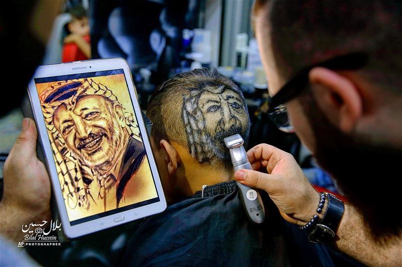 Muhannad Khaled Omar, shaves an image of the late Palestinian leader...