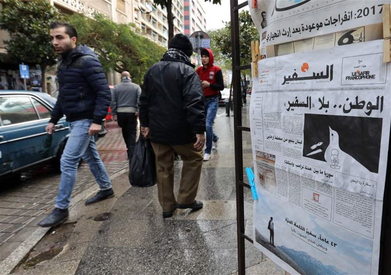 People walk past a newspaper stand, displaying the last issue of As-Safir newspaper, in Beirut’s Hamra neighborhood. (ANWAR AMRO/ AFP)