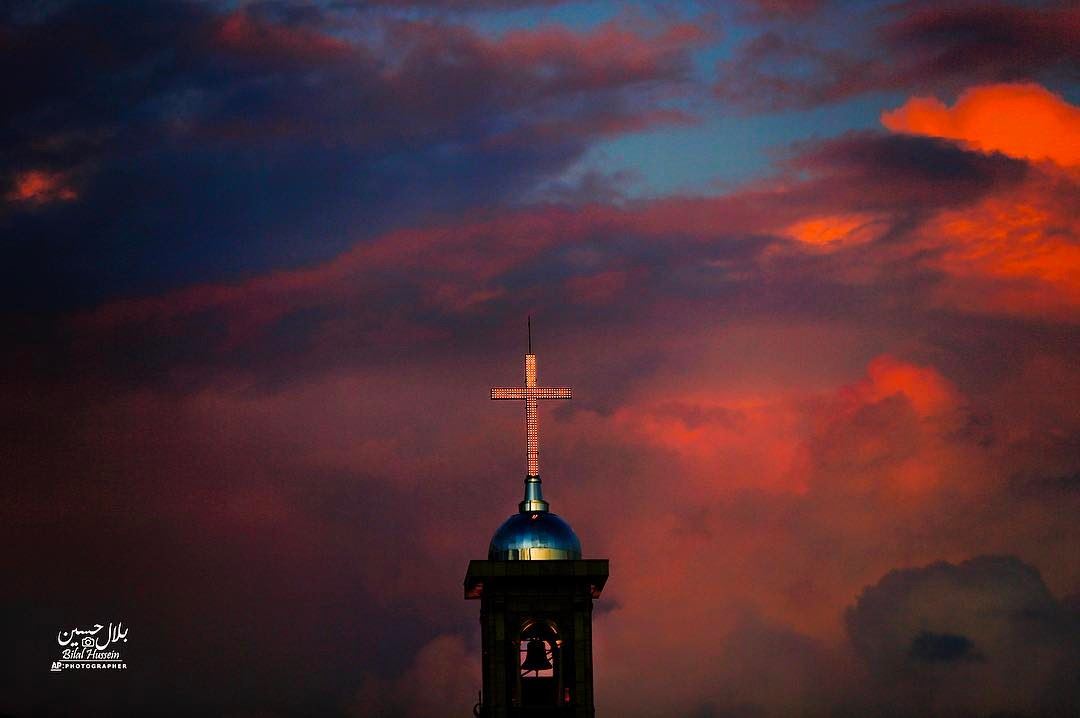 Saint George Maronite Cathedral’s cross is lit while heavy clouds darken...