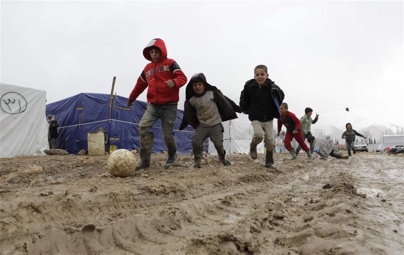 Syrian refugee children play soccer under the rain at a refugee camp in Deir Zannoun, Bekaa. (JOSEPH EID / AFP)
