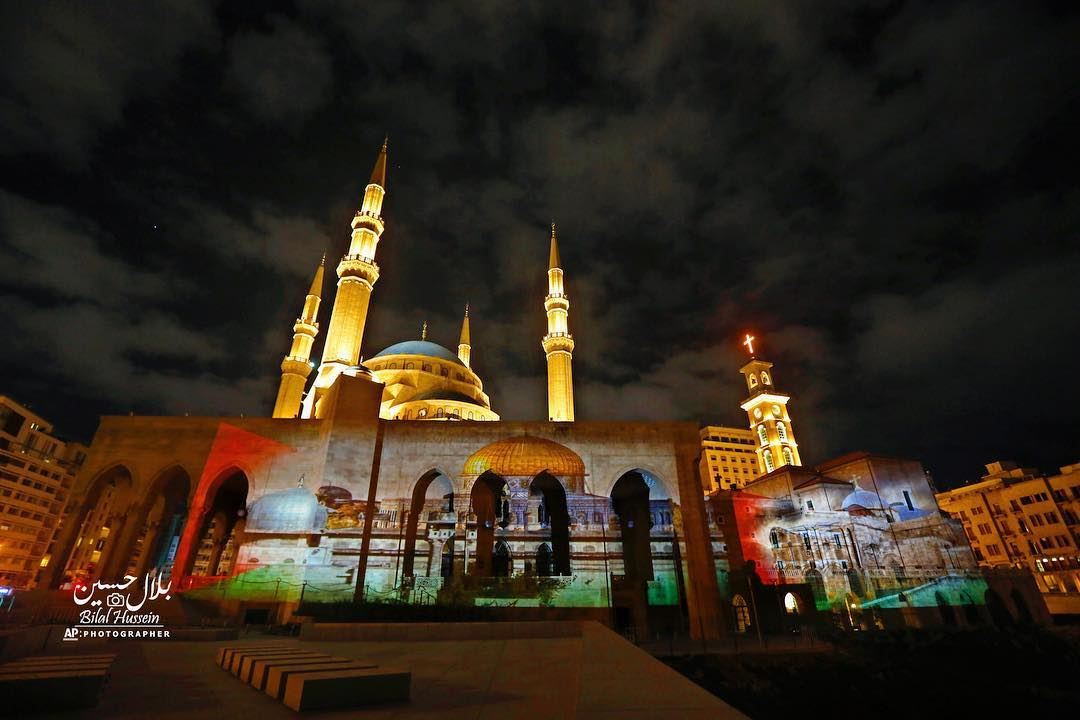 The Muhammad al-Amin Mosque, right, illuminated by a giant poster of the...