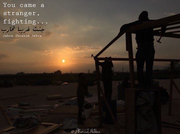 The picture is of a Syrian refugee setting up his tent in the new camp in "